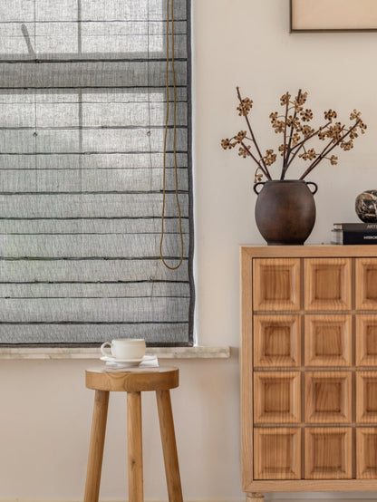 Natural ramie bamboo shades with black stripes in a minimalist room setting.