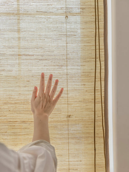 Natural ramie bamboo shades in cashew tone filtering light, with handcrafted texture, mildew-resistant.