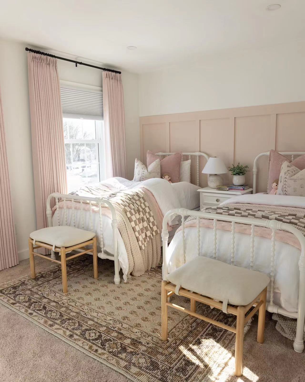 Elegant bedroom featuring EaseEaseCurtains pink pleated drapes, plush bedding with pink accents, and wooden stools on an ornate rug, showcasing influencer-approved style in a serene setting