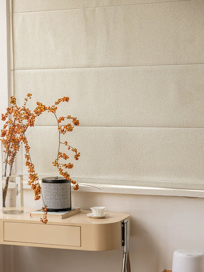 A table adorned with eco-friendly Roman blinds, a vase of flowers, and a cup.