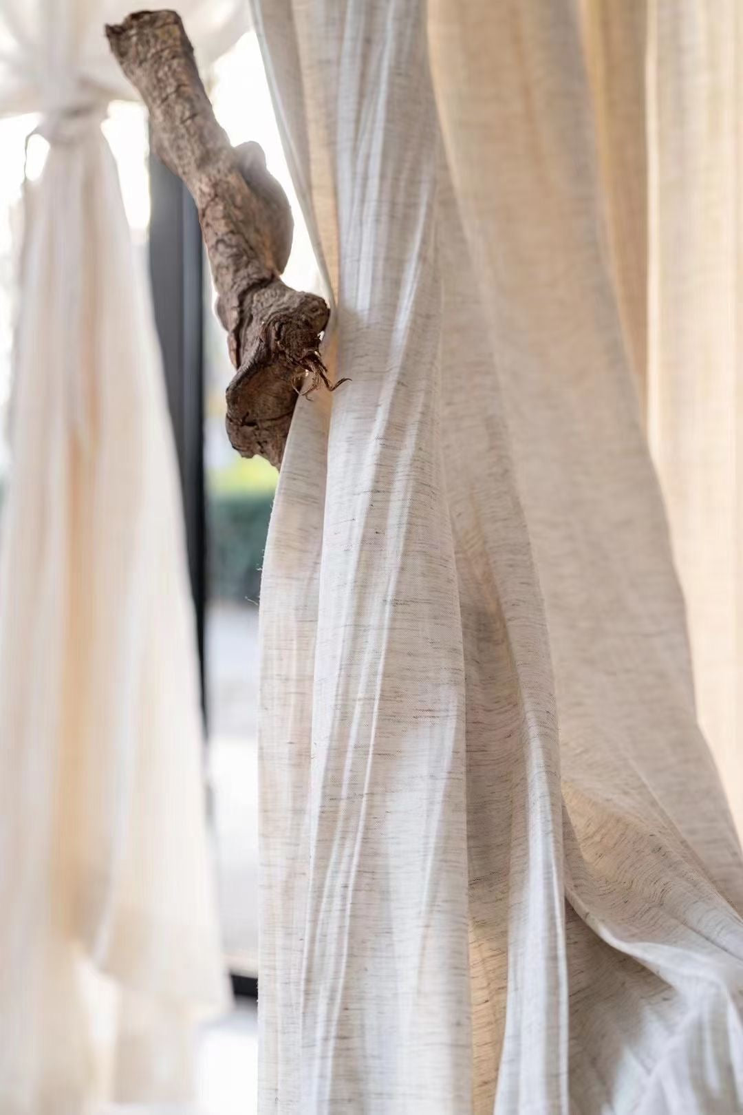 Lightweight crinkled linen gauze drapes hanging elegantly, providing semi-privacy and light-filtering in a breezy, airy atmosphere.