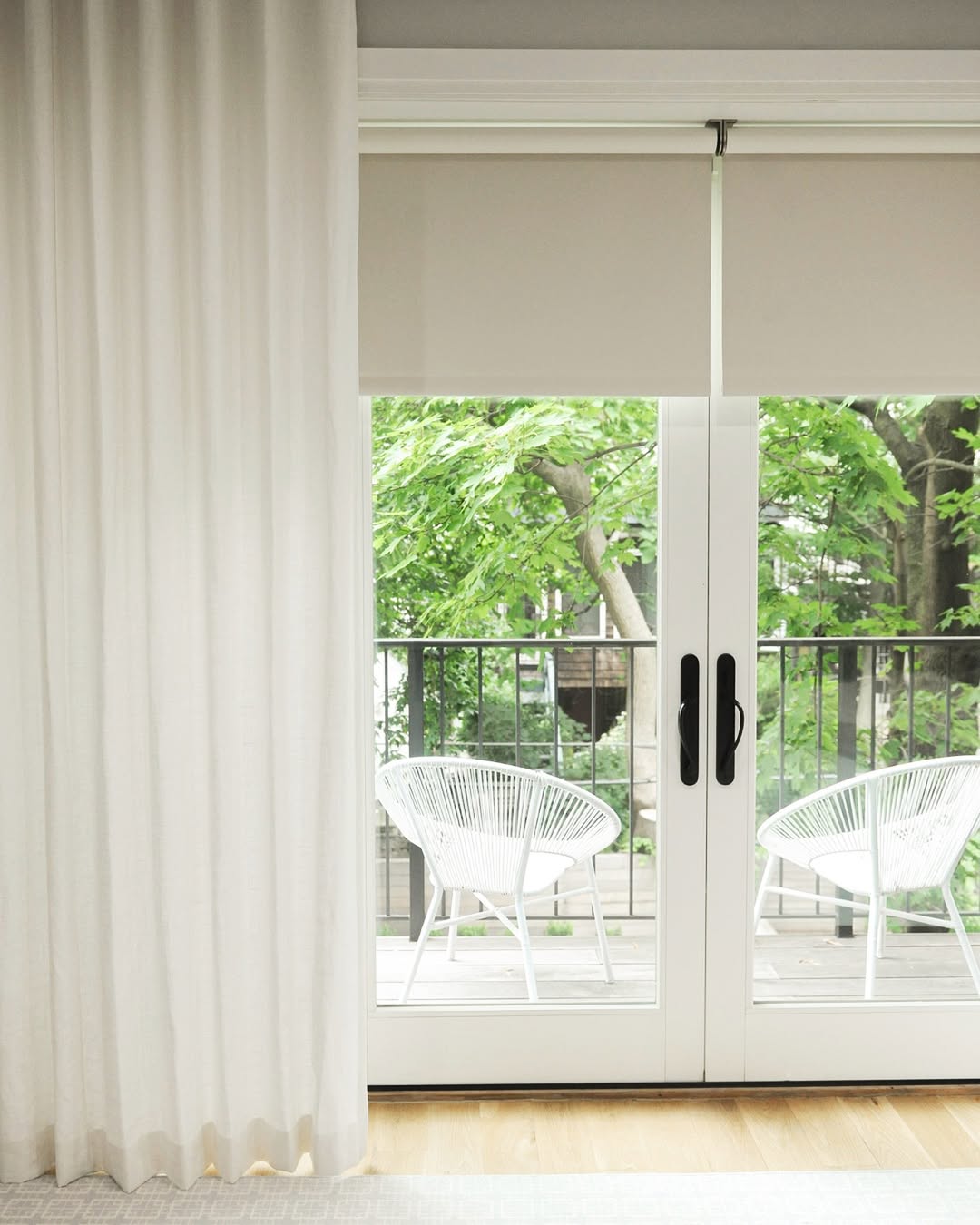 UV blocking solar shades on a window, cordless design with roller blinds, green view outside.