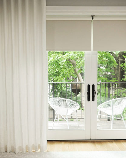 UV blocking solar shades on a window, cordless design with roller blinds, green view outside.