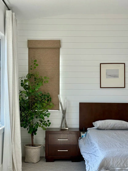 bedroom with bamboo roman shades on window next to nightstand and potted plant