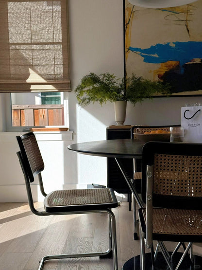 Bamboo roman shades in a dining room with natural light filtering through and modern furniture.