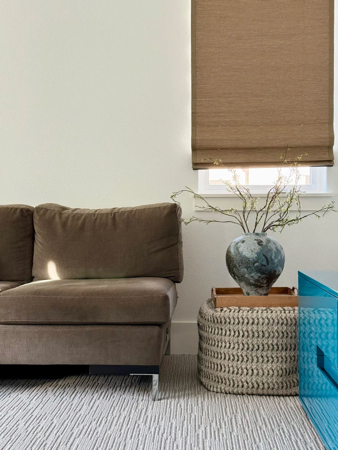 Brown bamboo roman shade in modern living room with sofa and decorative vase