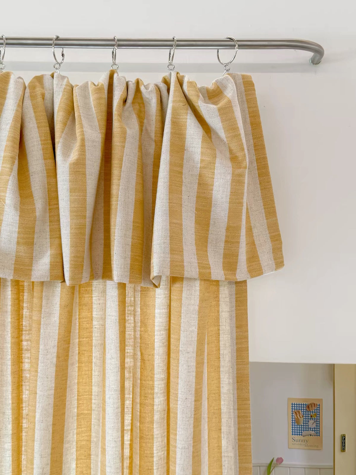 Butter yellow striped linen playroom curtain with ruffled top hung on a metal rod with rings