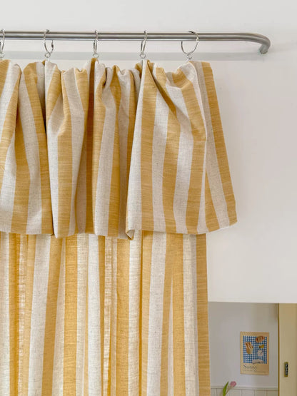 Butter yellow striped linen playroom curtain with ruffled top hung on a metal rod with rings