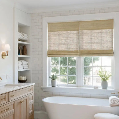 Beige natural ramie bamboo woven shades in a bright bathroom window above a soaking tub with wooden cabinetry and white tiled walls