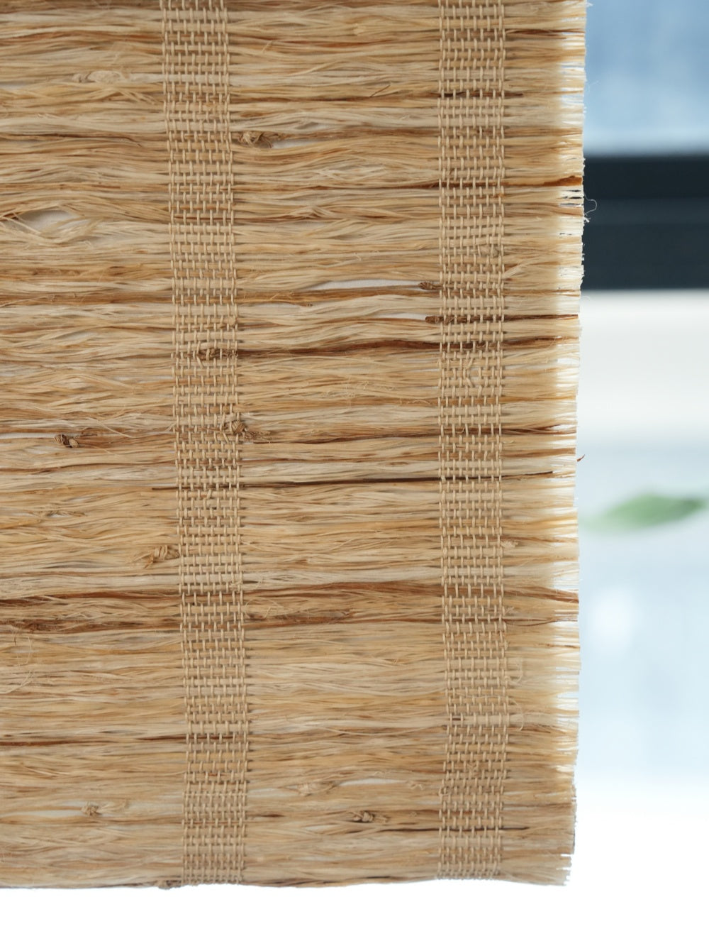 Close-up of natural cordless bamboo shades honey-toned woven shades made from 100% ramie fiber with breathable, textured weave.