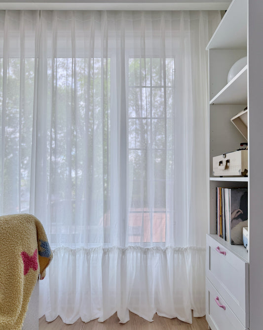 Cream sheer curtains with ruffled hem in a princess room window