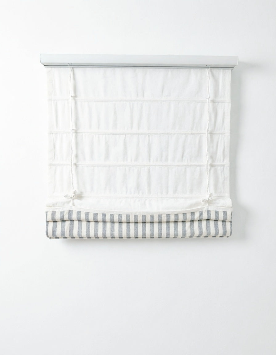 Custom hobbled roman shades in white fabric with a gray and white striped bottom band and soft layered folds