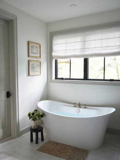 Custom Roman Shade in natural white linen with soft horizontal folds and a cordless design over a bathroom window