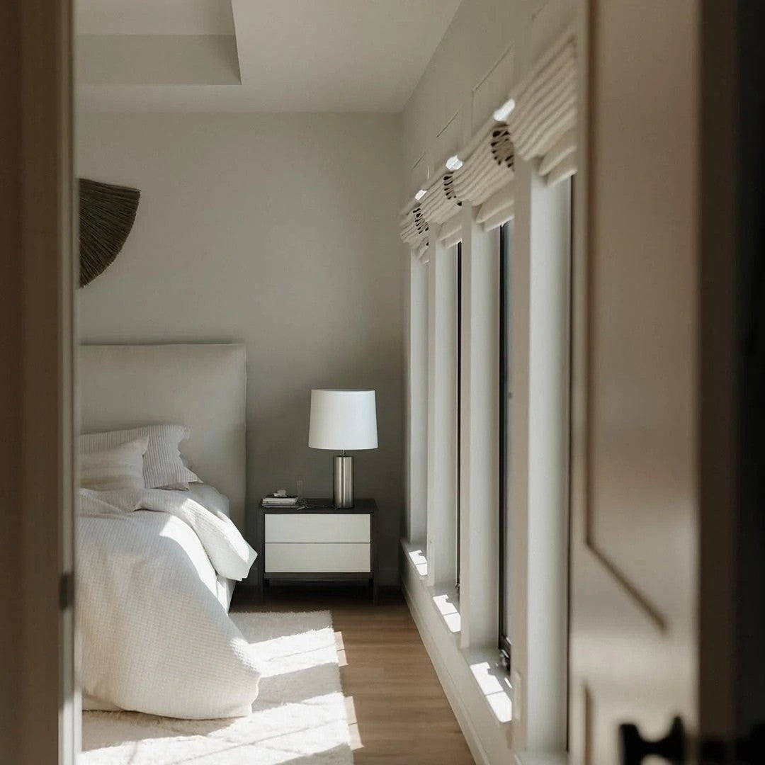 Modern bedroom with cordless custom roman shades on windows, neutral decor, and natural light filtering through light-filtering fabric shades