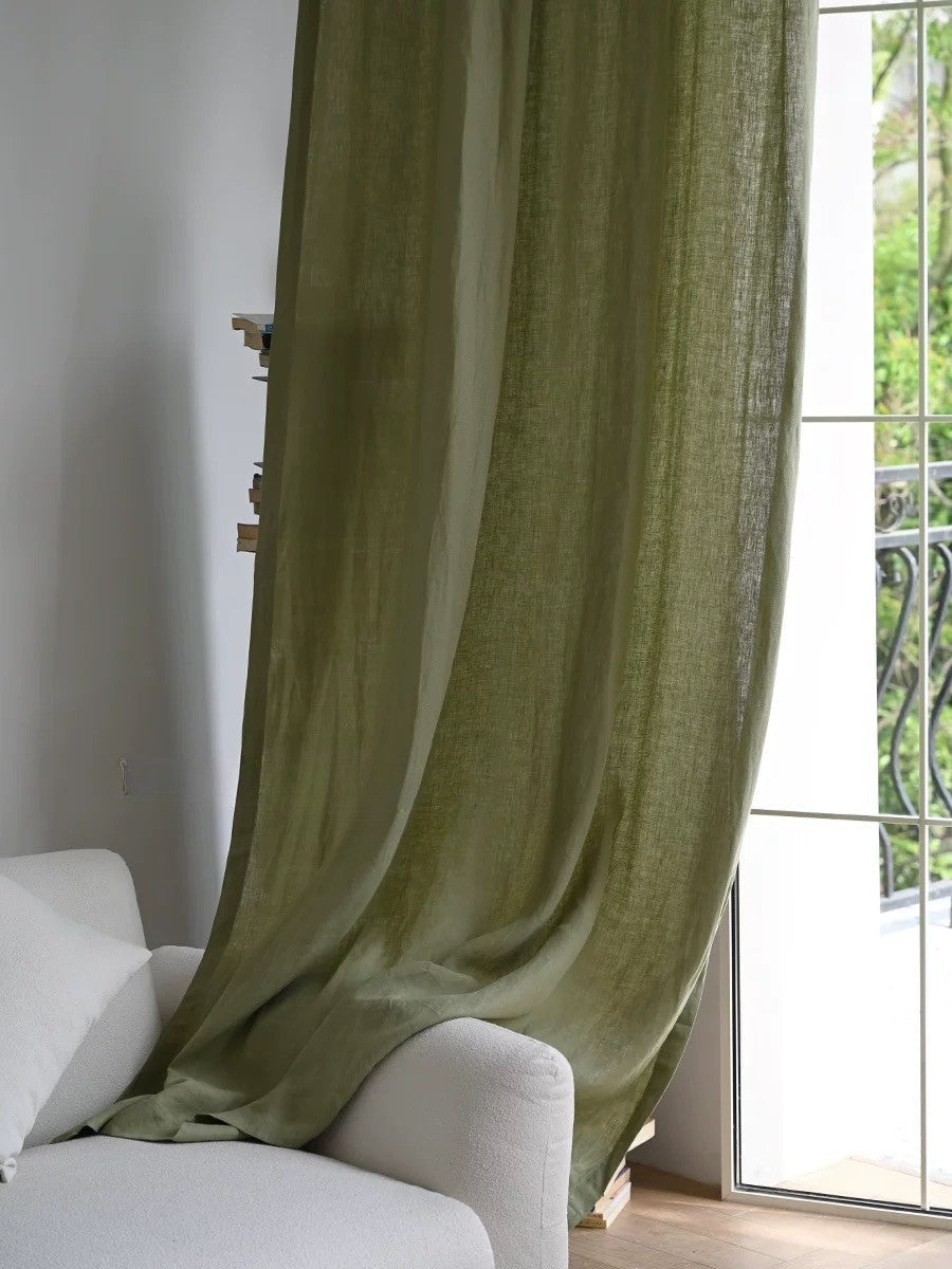 Sage green linen curtains hanging beside a window over a white sofa in a living room