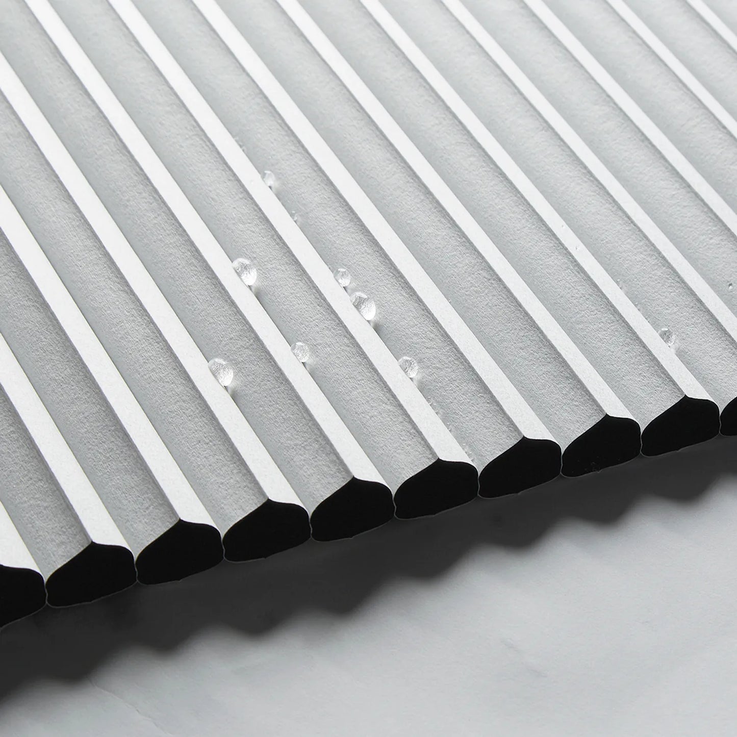Close-up of white waterproof honeycomb blind with water droplets, showcasing high-quality cellular structure and ultrasonic precision edges