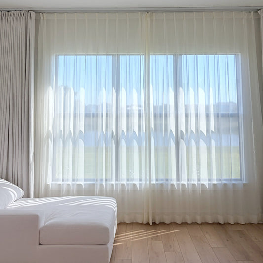 Luxury sheer curtains with delicate shimmering threads glowing in sunlight in a sunroom