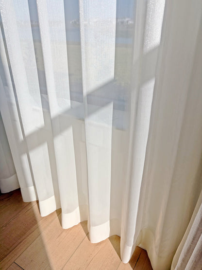 Luxury sheer curtains with shimmering threads glowing in sunroom window light