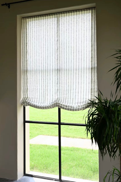 Gray striped roman shades in sheer linen with fine vertical stripes and soft scalloped Roman folds, filtering daylight.