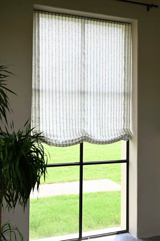 Gray striped roman shades in sheer linen with fine vertical stripes and soft scalloped Roman folds, filtering daylight.