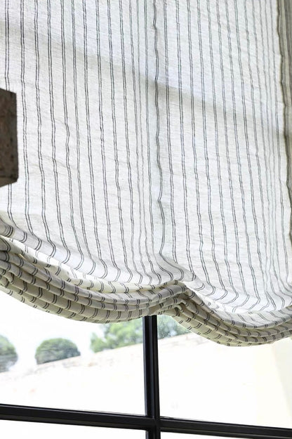 Gray striped roman shades in sheer white fabric with fine vertical gray lines and soft, gathered Roman folds