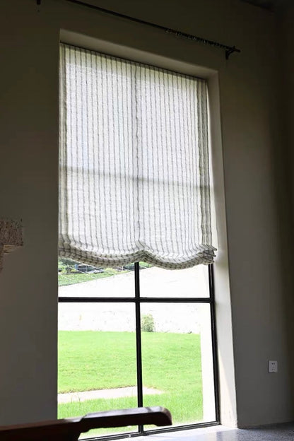 Gray striped roman shades in sheer textured fabric, softly gathered into a scalloped Roman fold at the bottom.