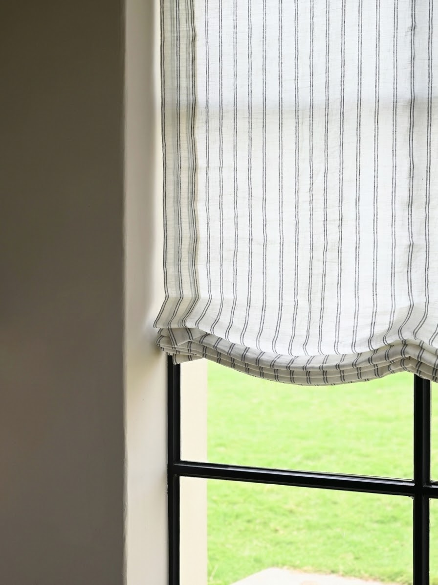 Gray striped roman shades in sheer linen with fine vertical stripes and a softly gathered, curved bottom edge.