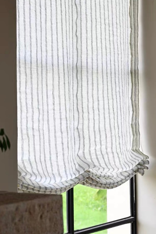 Gray striped roman shades in sheer white linen with narrow gray vertical lines and softly gathered Roman folds