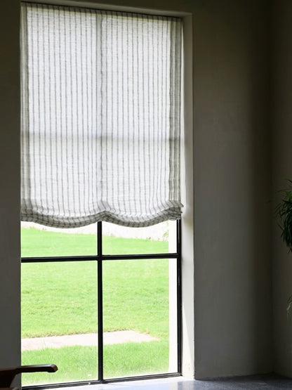 Gray striped roman shades in sheer white fabric with fine vertical gray stripes and softly scalloped Roman folds