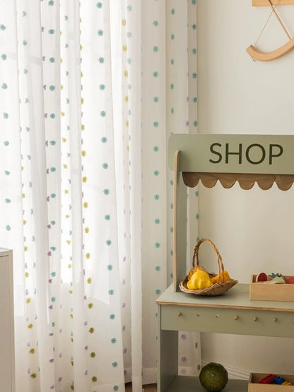 Colorful kids curtains with whimsical rainbow pom-poms in sheer fabric for bright, playful rooms
