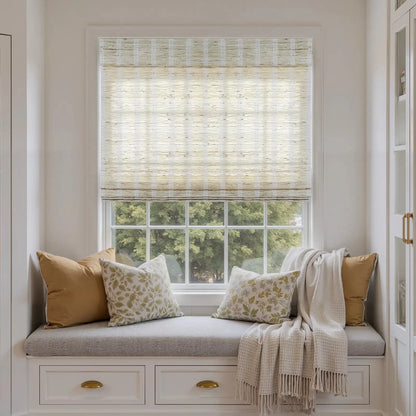 Natural ramie woven wood shades in almond color over a window bench with beige and floral pillows and a soft throw blanket