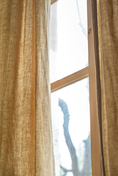 mustard yellow curtains made of 100% French linen with soft natural texture and warm muted color by a window