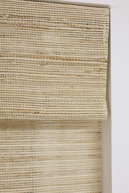 Natural Ramie Bamboo Roman Shades in beige, with a tightly woven natural fiber texture and softly folded sections.