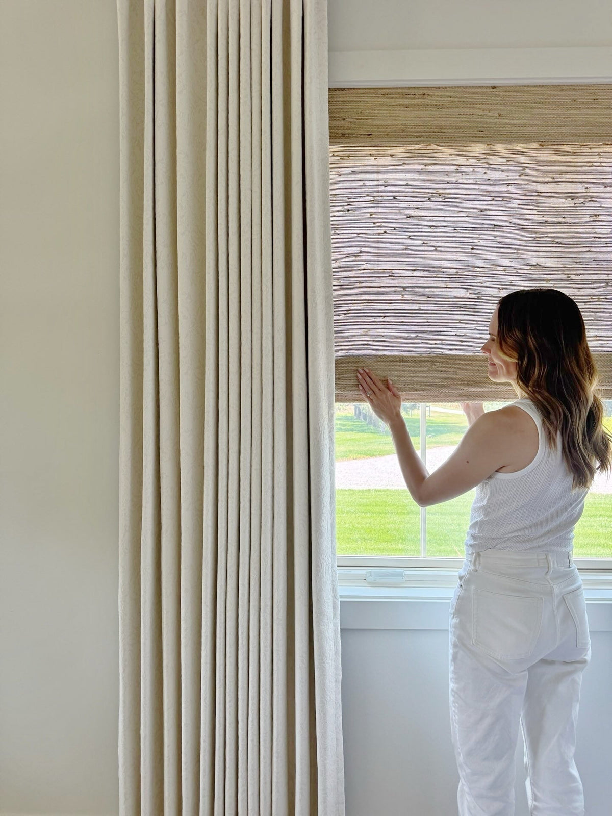 Natural Ramie Bamboo Roman Shades in beige, woven with fine horizontal fibers and a textured finish, partially lowered over a window.