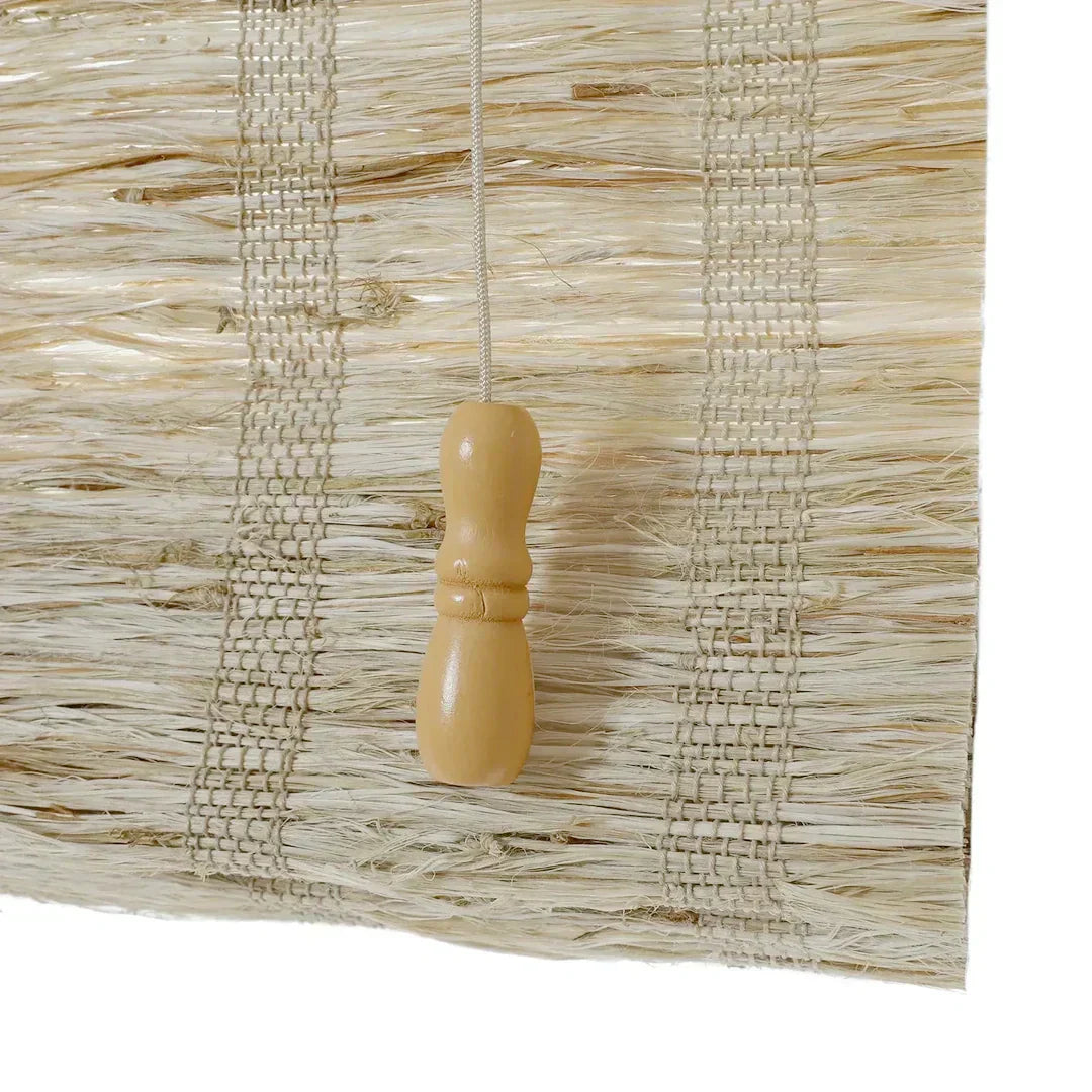 Close-up of almond-colored natural woven shades with handwoven texture and wooden pull handle