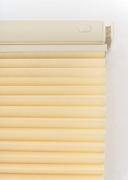 No drill honeycomb shades in soft cream fabric with a cordless top rail and pleated cellular design