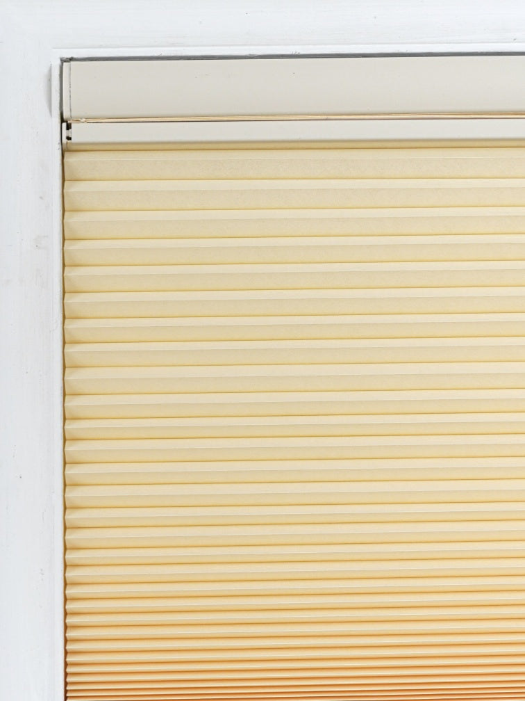 No drill honeycomb shades in a cream fabric with horizontal pleats and a cordless, tool-free design