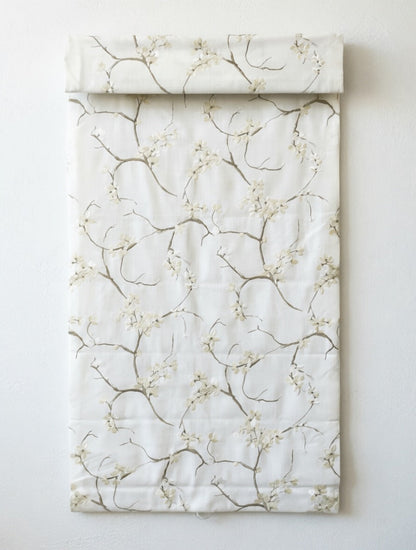Patterned Roman Shades in ivory linen with delicate embroidered branches and blossoms, flat-fold design