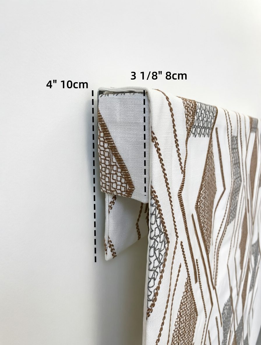Patterned Roman Shades in white linen with raised brown geometric embroidery and a folded fabric valance detail