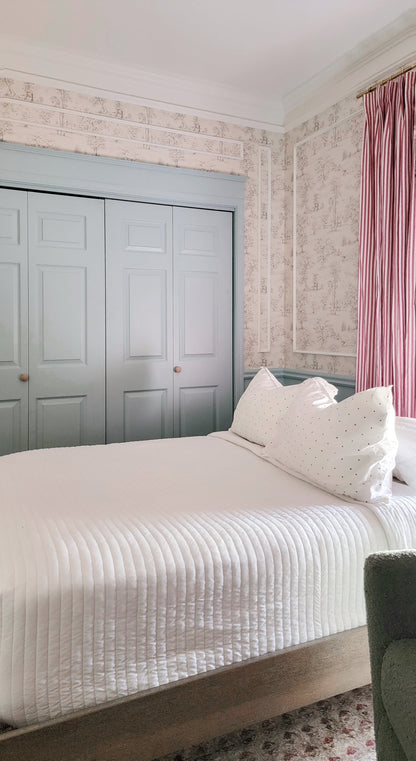 bedroom with white bedding and pink relaxed roman shades on window