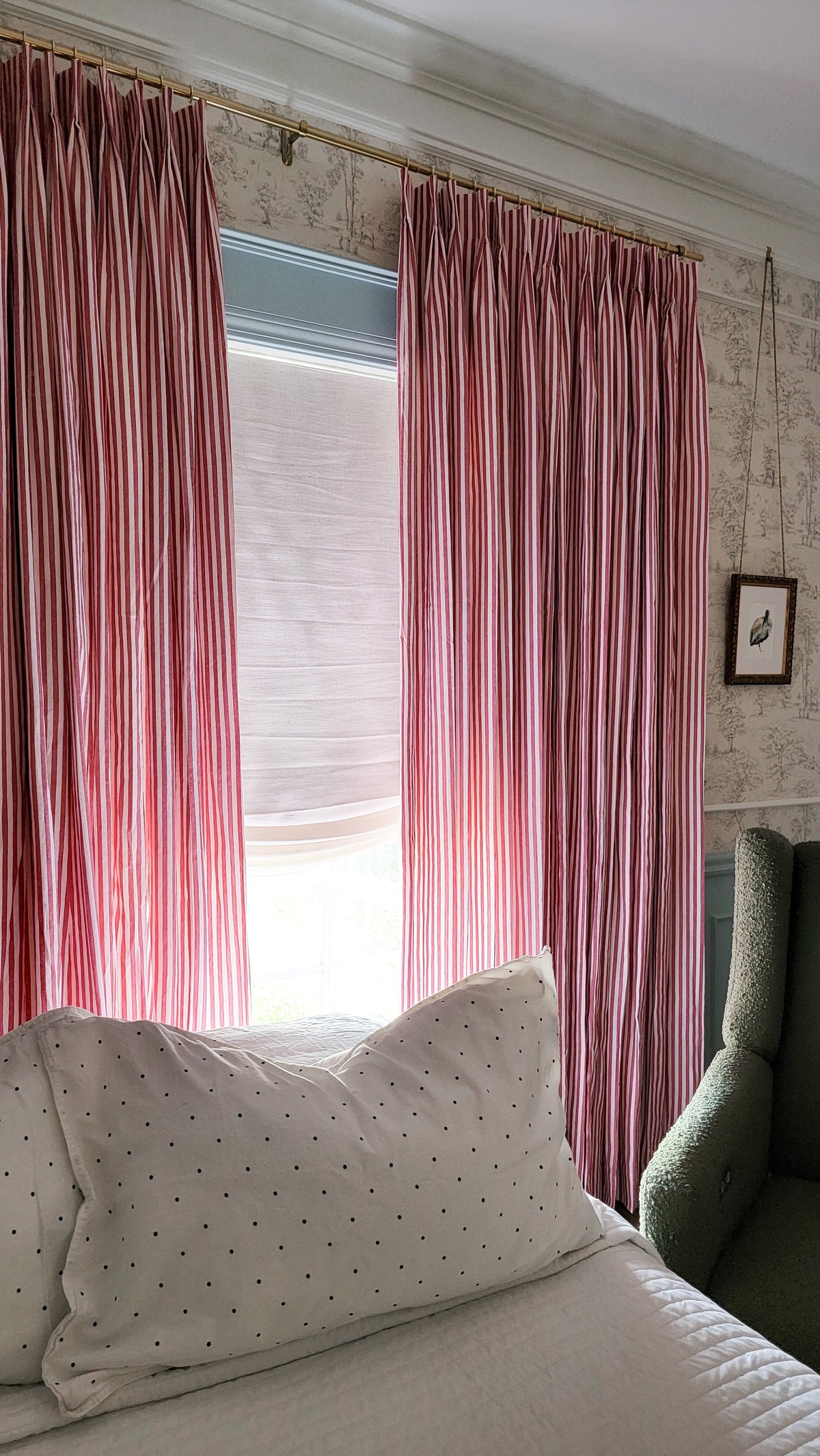 Red and white striped relaxed Roman shades with a soft curved bottom installed on a window in a cozy bedroom setting.