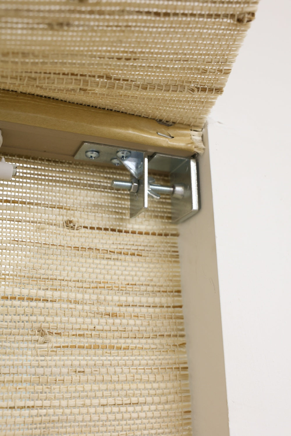 Beige natural Roll Up Bamboo Shades with metal mounting bracket installed on window frame
