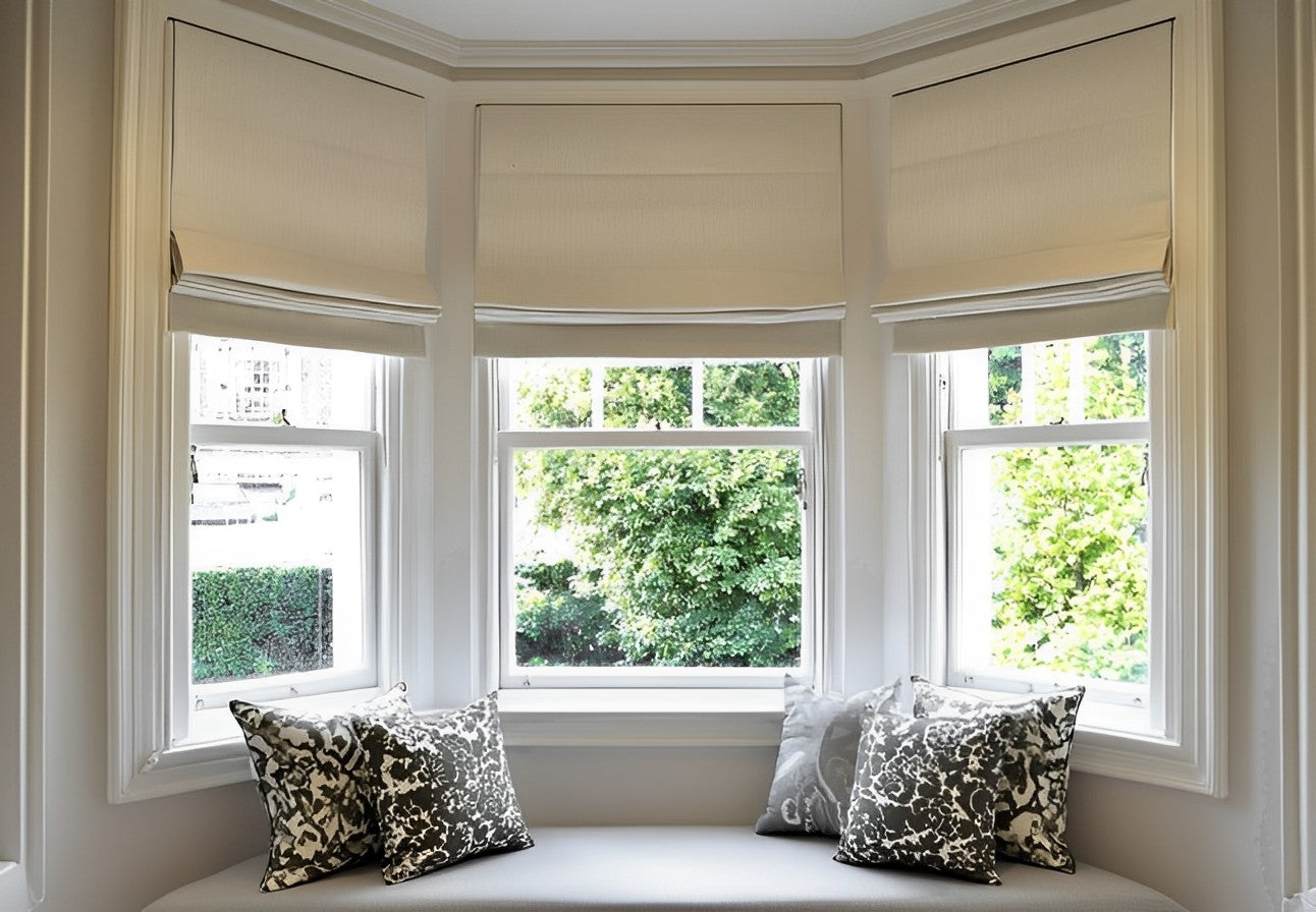 Custom cordless blackout Roman shades in a bay window setting.