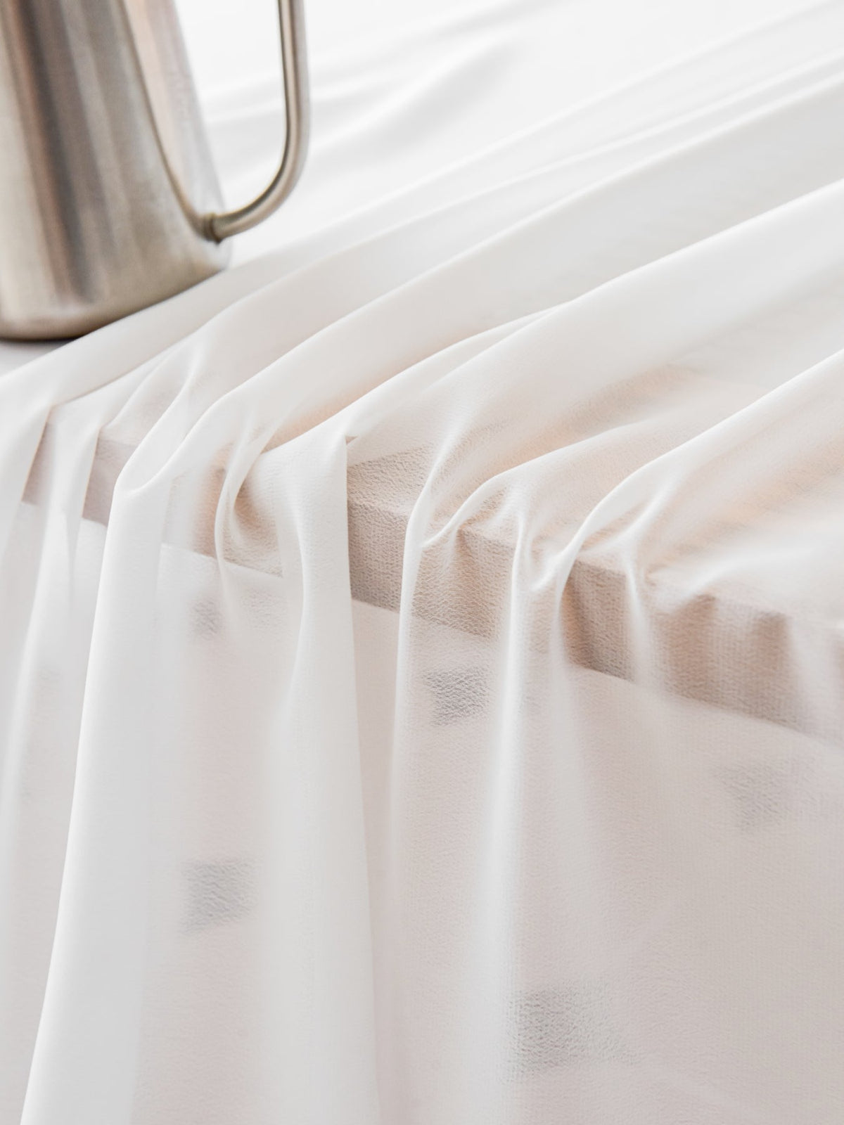 Linen cafe curtains in white filtering daylight on small bathroom window with elegant drape.