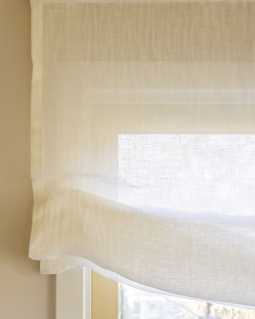 Soft sheer Roman shade in 100% pure linen with gentle folds filtering light and providing privacy