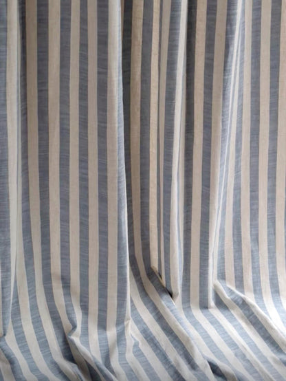 Close-up of coastal blue and white ticking stripe linen curtain fabric with soft drape