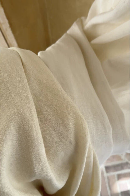 Ivory white linen curtains made from 100% French linen hanging in a bright living room