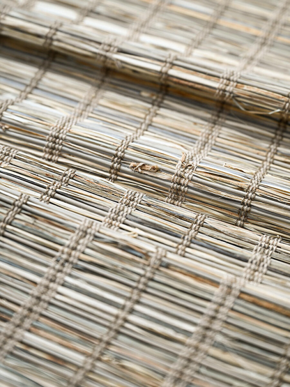 Woven Roman Shades in natural jute with a warm cinnamon tone and textured, handwoven grid pattern