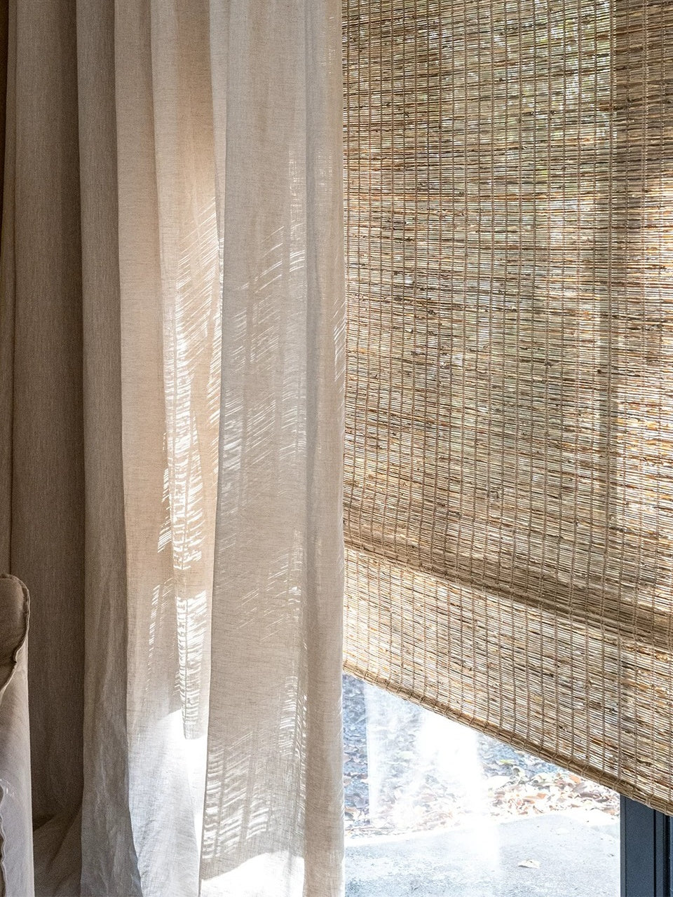Woven Roman Shades in natural beige jute, featuring a textured woven pattern and horizontal fold
