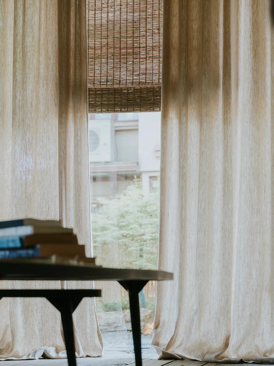 Woven Roman Shades in natural jute with a warm cinnamon tone and textured woven detail beside sheer curtains